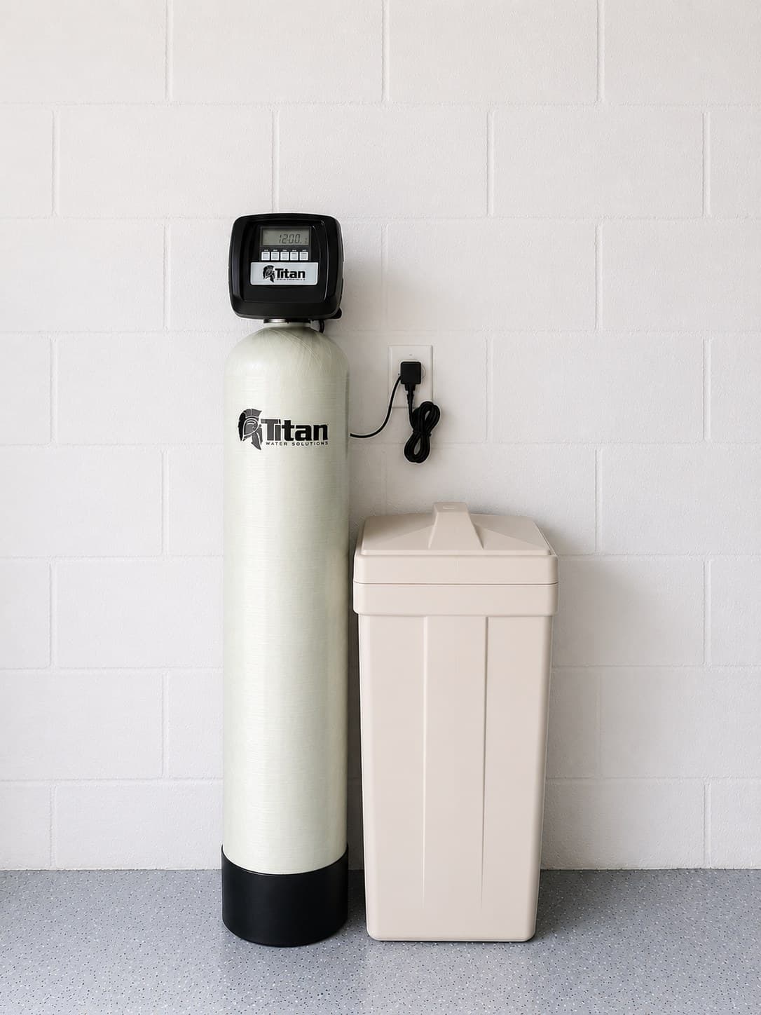 A Titan water softener and salt tank installed against a white cinderblock garage wall