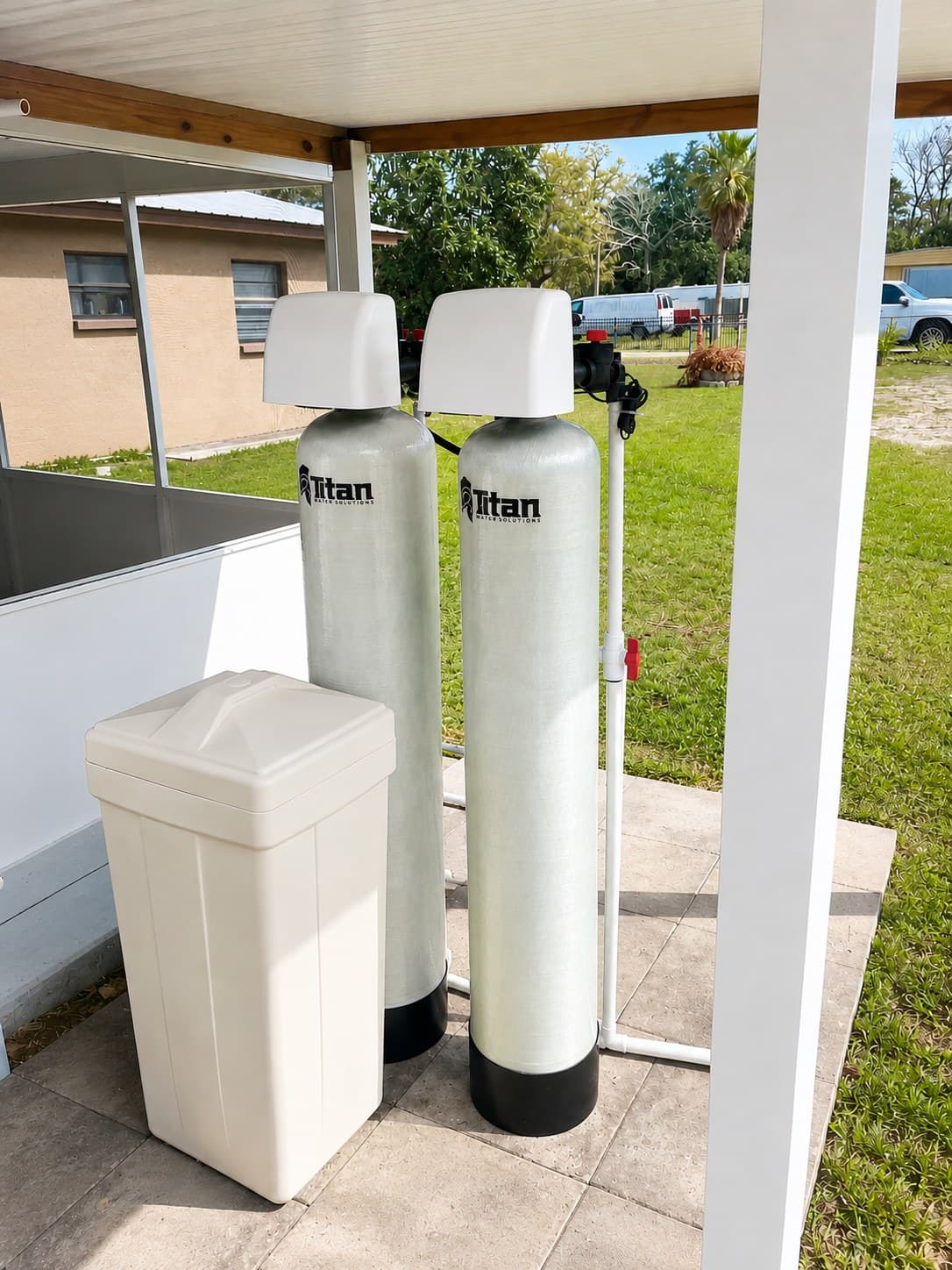 A Titan two-tank well water system and salt tank installed under a covered patio