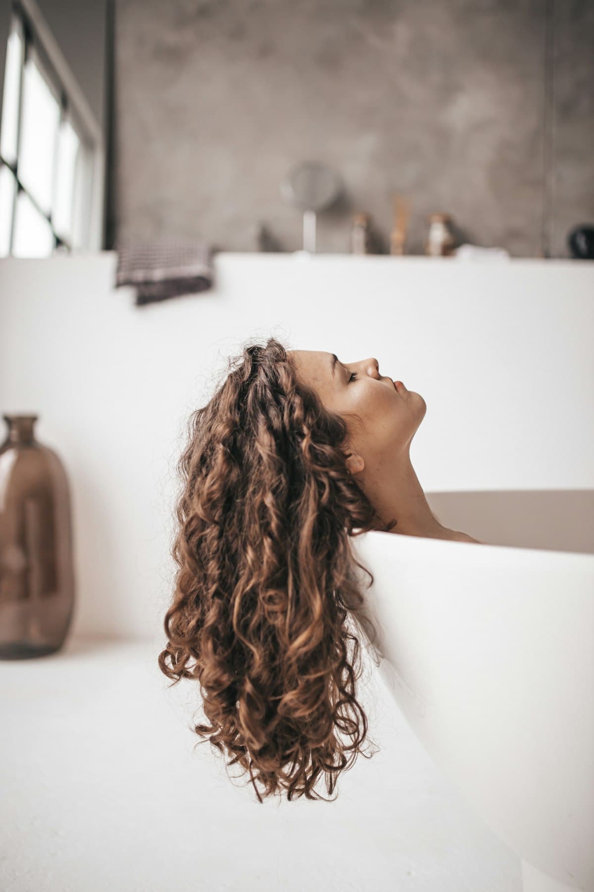 A woman relaxing in a bathtub with her hair over the edge