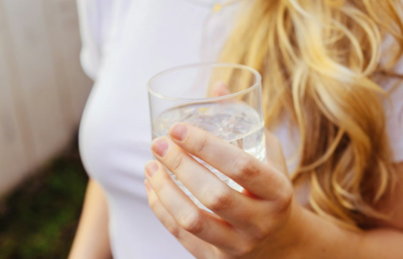 A woman holding a glass of cold, clean drinking water